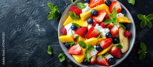 Healthy fruit salad with varied ingredients, mint, and sour cream. Room for text. Overhead view.