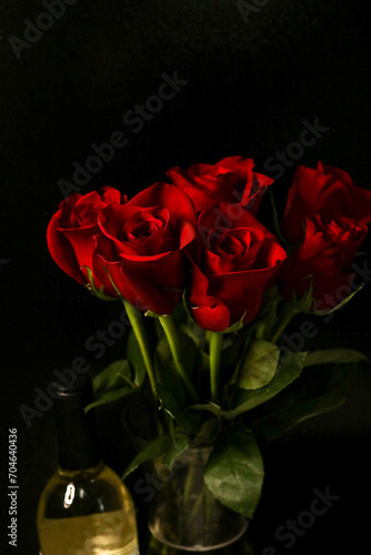 Dark red roses with bottle of wine with dark background  romantic setting 