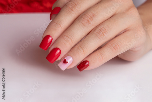  Beautiful female hand with red manicure nails, heart and Valentine's day design 