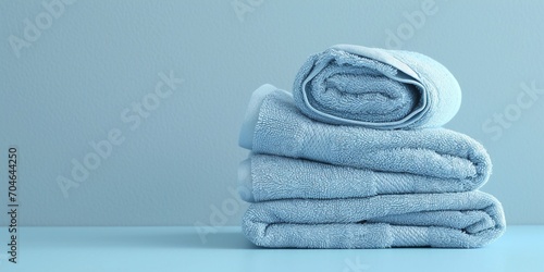Light blue spa towels pile, bath towels lying in a stack on light blue peaceful background with copy space. photo