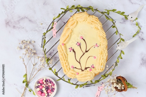 Mazurek, a Polish Easter sweet made from shortcrust pastry in the shape of an egg with Easter decoration on a metal lattice on a light background. Polish cuisine. photo