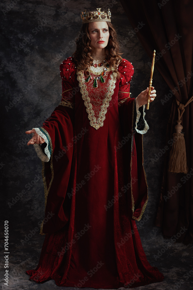 Full length portrait of medieval queen in red dress with wand
