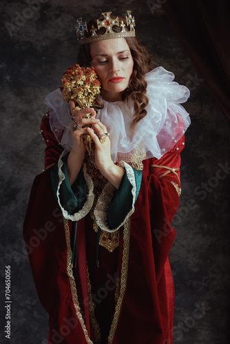 pensive medieval queen in red dress with dried flower