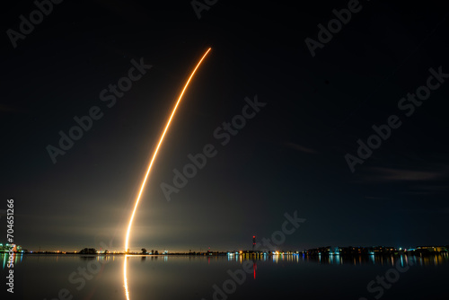 Rocket On Its Way to Space Lighting the Night Sky and Reflecting On The Water