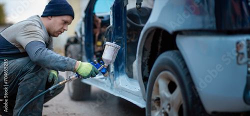 Master car painter paints a car with a spray gun. Car painting at home. photo