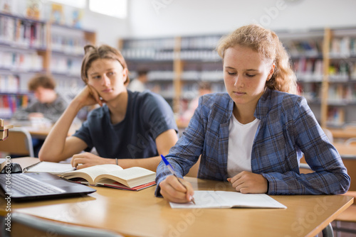 Schoolgirl and schoolboy are sitting together at the same desk at a lesson in a school class