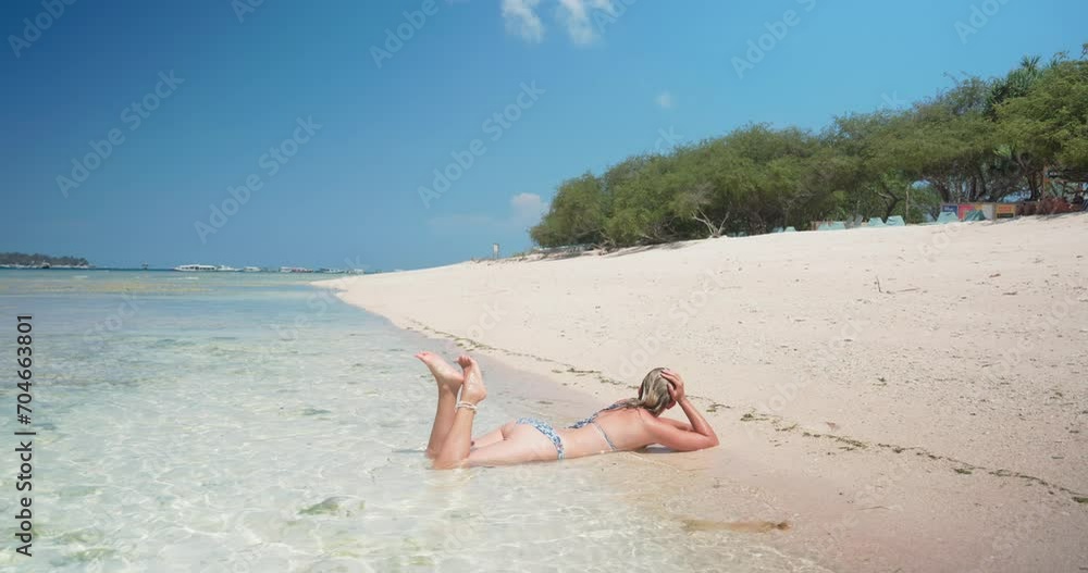 A young woman in a swimming suit is in the shallow sea of a sand beach in Gili Meno, Indonesia A young woman in a swimming suit is in the shallow sea of a sand beach in Gili Meno, Indonesia