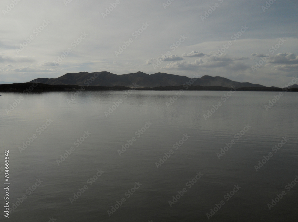 Cloudy day on a calm lake with mountains in the background