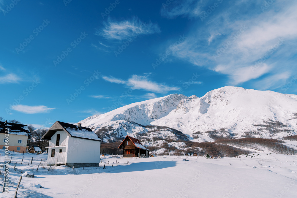 Two-storey cottages in a mountain village at the foot of snow-capped mountains
