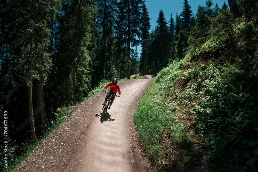Downhill mountain biking on a shaped bike park trail in Austria, sunny blue sky day, bike leaning in the curve. Downhill mountain biking on a shaped bike park trail in Austria, sunny blue sky day, bike leaning in the curve.