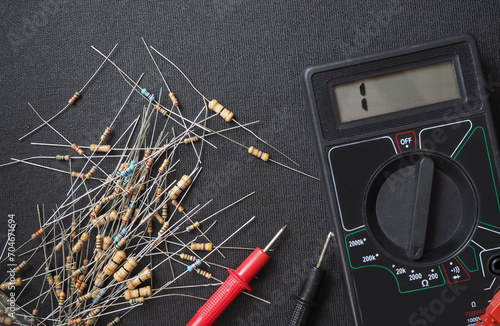 Electrical resistors and ohmmeter on the workbench.  photo