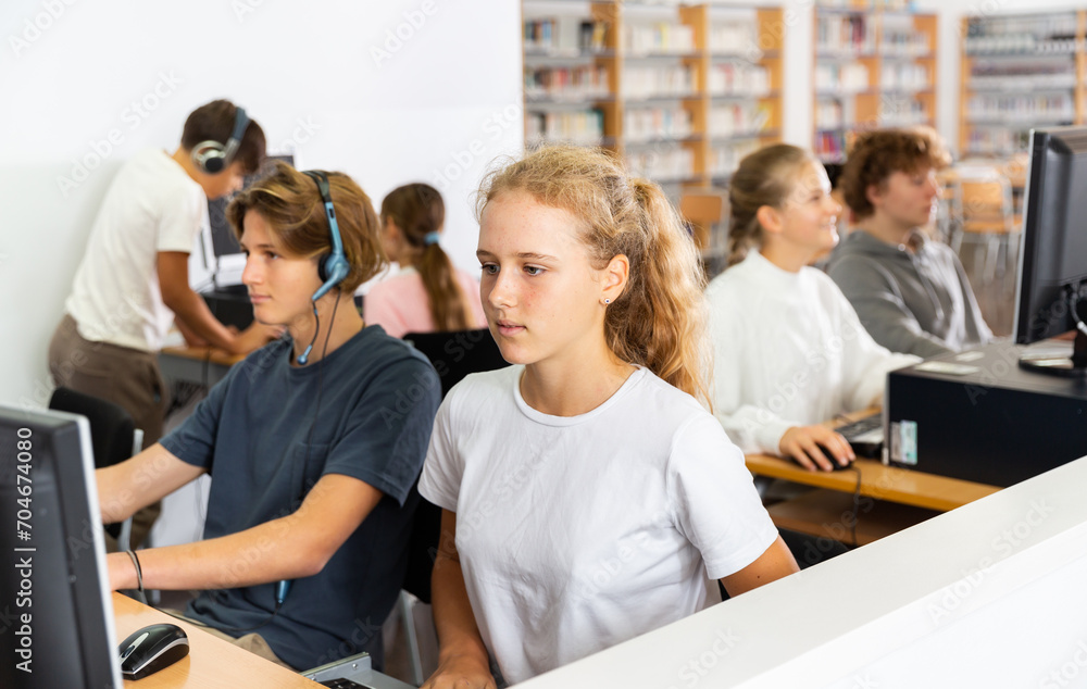 Fototapeta premium Pupils using computers at lesson, teacher teaching them in classroom