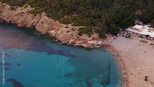 Island Ibiza beach sailing boats in the bay. Smooth aerial top view flight drone photo