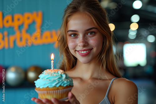 Siła Uśmiechu, Słodyczy i Urodzin. Piękna dziewczyna z babeczką i napisem "Happy Birthday" w tle – uśmiech, radość i świętowanie w atmosferze zdrowego trybu życia.