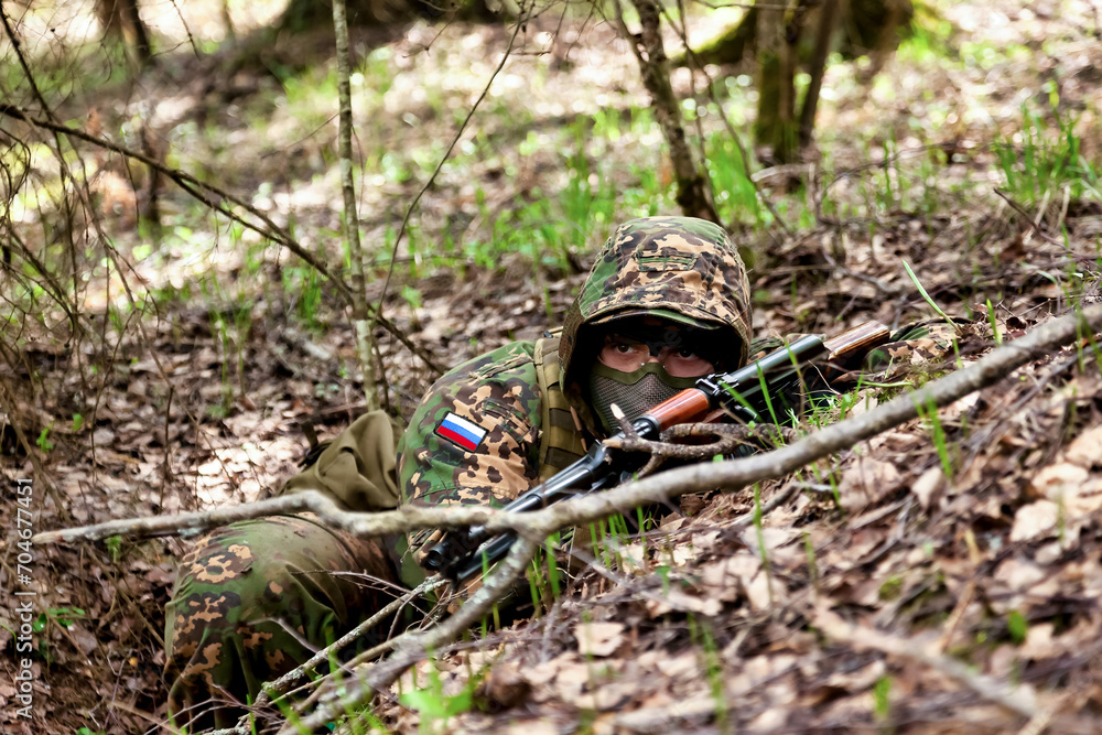 Ukrainian soldier man dressed military disguise camouflage uniform with weapon in woodland at nature background, looking away. Male border guard in country border with autogun on war. Copy text space