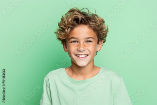 Portrait of a cute little boy with curly hair smiling on a green background