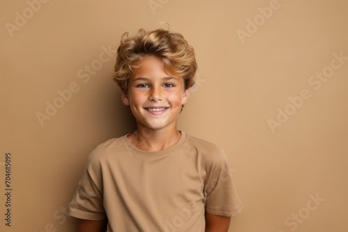 Portrait of a cute little boy with blond curly hair on a brown background