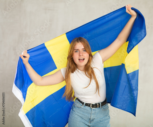 Smiling female fan of Sweden cheers for winning holding a flag