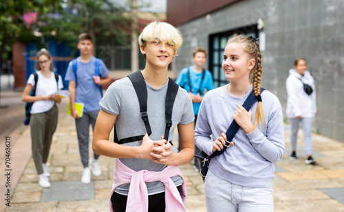Fototapeta Naklejka Na Ścianę i Meble -  Young students with backpacks and notebooks walk down the street