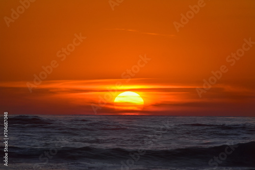 Fototapeta Naklejka Na Ścianę i Meble -  Embark on a journey of serenity with this captivating sunset photograph taken on a pristine Costa Rican beach. The awe-inspiring beauty of the sun setting over the horizon transforms the sky into a vi