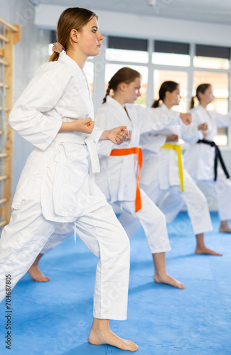 Kata karate woman teacher conducts female classes and performs movements and fighting techniques together with young girls students to prepare them for competitions.