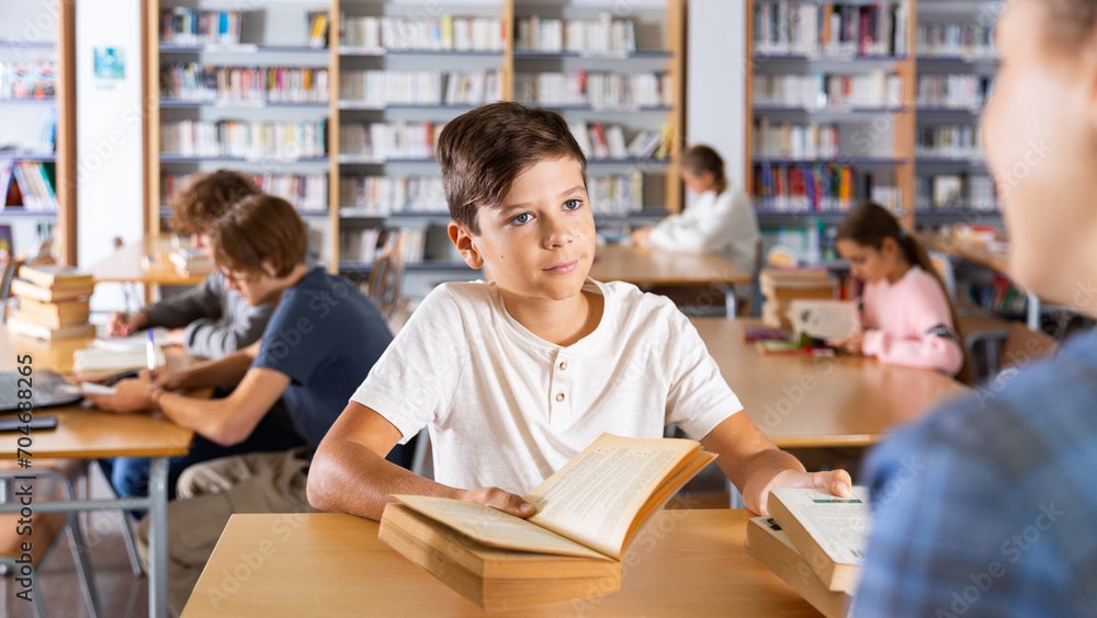 Boy gives the read books to the librarian in the school library