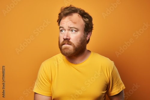 Portrait of a red-bearded man in a yellow T-shirt on a yellow background