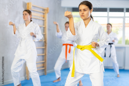 In gym, certified woman master coach conducts karate kata lesson with young female students group and shows sequence of actions when conducting close fight