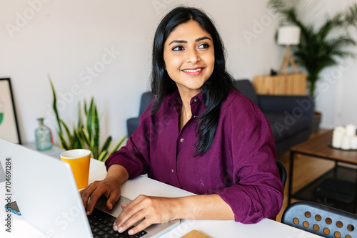 Thoughtful young indian woman working on laptop. Professional business ethnic woman working on laptop at home.