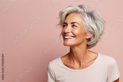 Portrait of a smiling senior woman looking up over pink background.