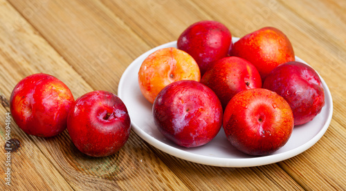 Juicy red plums on wooden background