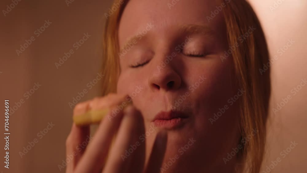 A smiling young woman enjoying a heart shaped Valentine's Day cookie A smiling young woman enjoying a heart shaped Valentine's Day cookie