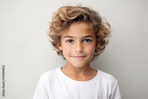 Portrait of a cute little boy with curly hair on a gray background photo