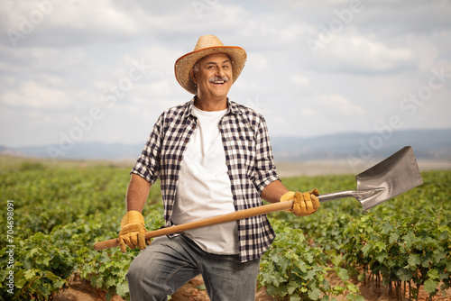 Farmer with a straw hat holding a shovel on a field