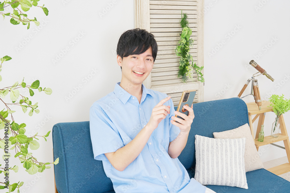 自宅でスマートフォンを使う男性　カメラ目線