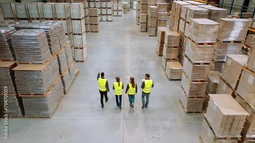Top view of full team of warehouse employees walking in warehouse. Team of workers, managers, female director in modern industrial factory, heavy industry, manufactrury.