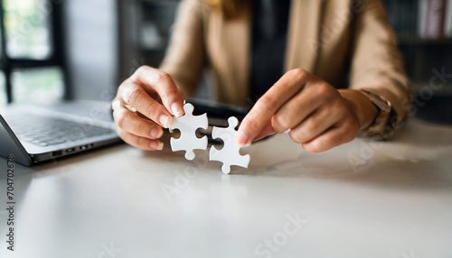 Businesswoman's hand assembles jigsaw puzzle on desk, symbolizing strategy, success, and problem-solving in business