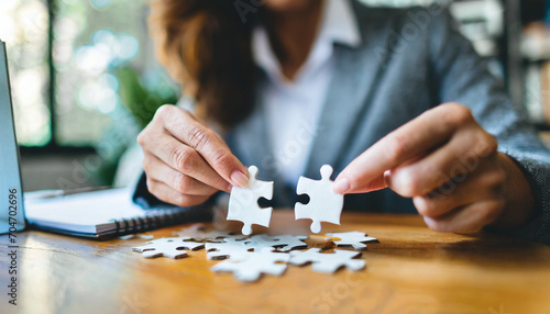 Businesswoman's hand assembles jigsaw puzzle on desk, symbolizing strategy, success, and problem-solving in business photo