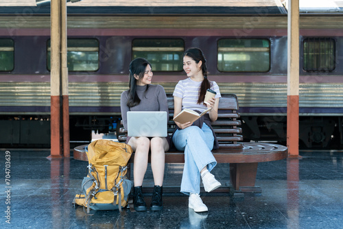 Woman traveler with backpack using laptop to planning vacation on holiday relaxation at the train station