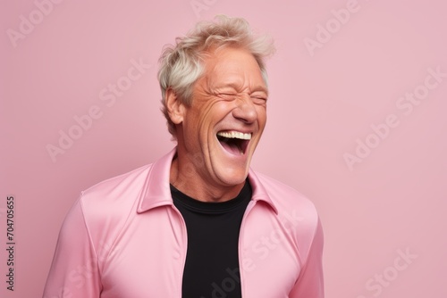 Portrait of a happy senior man laughing isolated over pink background.