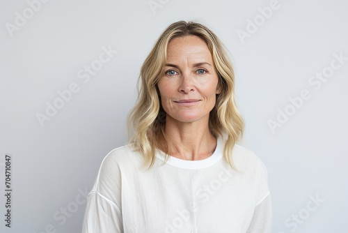 Portrait of mature woman looking at camera with serious expression against grey background © Chacmool