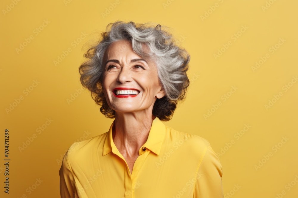 Portrait of smiling senior woman looking up at copy space on yellow background Portrait of smiling senior woman looking up at copy space on yellow background