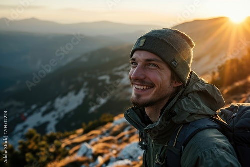 Smiling young man enjoying a solo hike in the mountains, breathtaking view. © furyon
