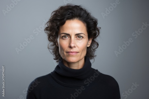 Portrait of a beautiful middle-aged woman in a black sweater on a gray background
