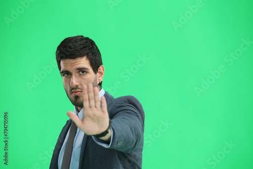 A man in an office suit on a green background close-up shows a stop sign