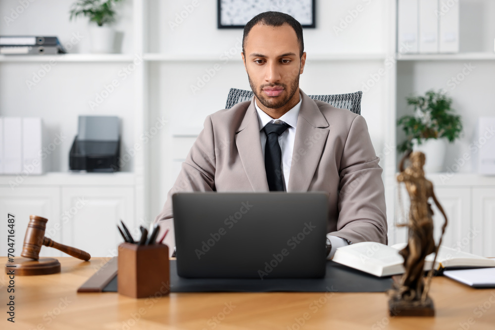 Serious lawyer working with laptop at table in office