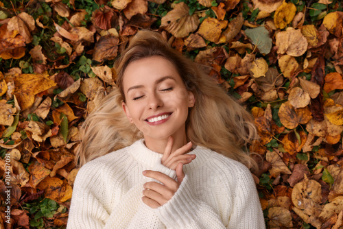 Smiling woman lying among autumn leaves outdoors  top view