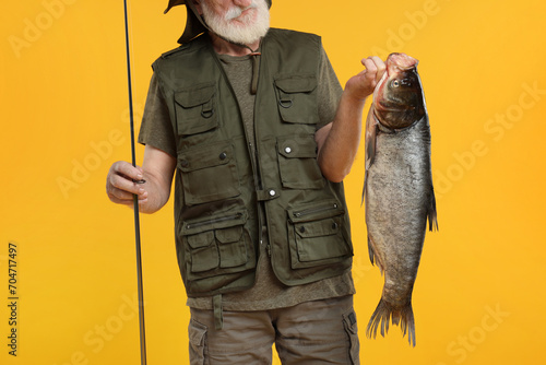 Fisherman with rod and catch on yellow background, closeup