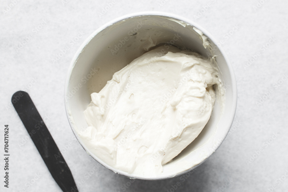 Top view of cream buttercream in a white mixing bowl, silky smooth american buttercream in a ceramic bowl, overhead view of smooth buttercream