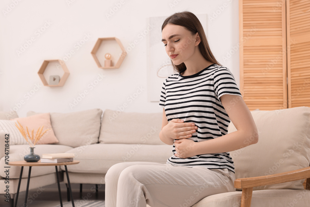 Young woman suffering from stomach pain at home. Space for text Young woman suffering from stomach pain at home. Space for text